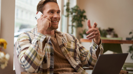 Handsome businessman in coffee shop, sitting in cafe with laptop and calling someone, Man talking on the phone with client, making enquiry about project, talking to coworker while working remotely.